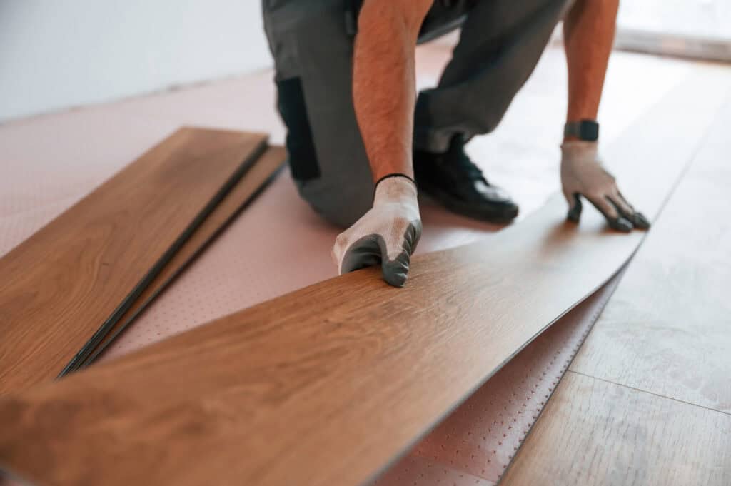 Worker installing wooden flooring in a home renovation project.