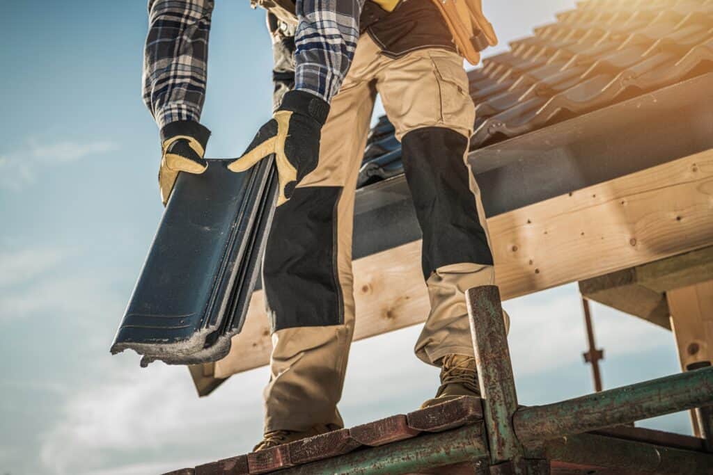 Roofing contractor installing shingles on a residential roof.