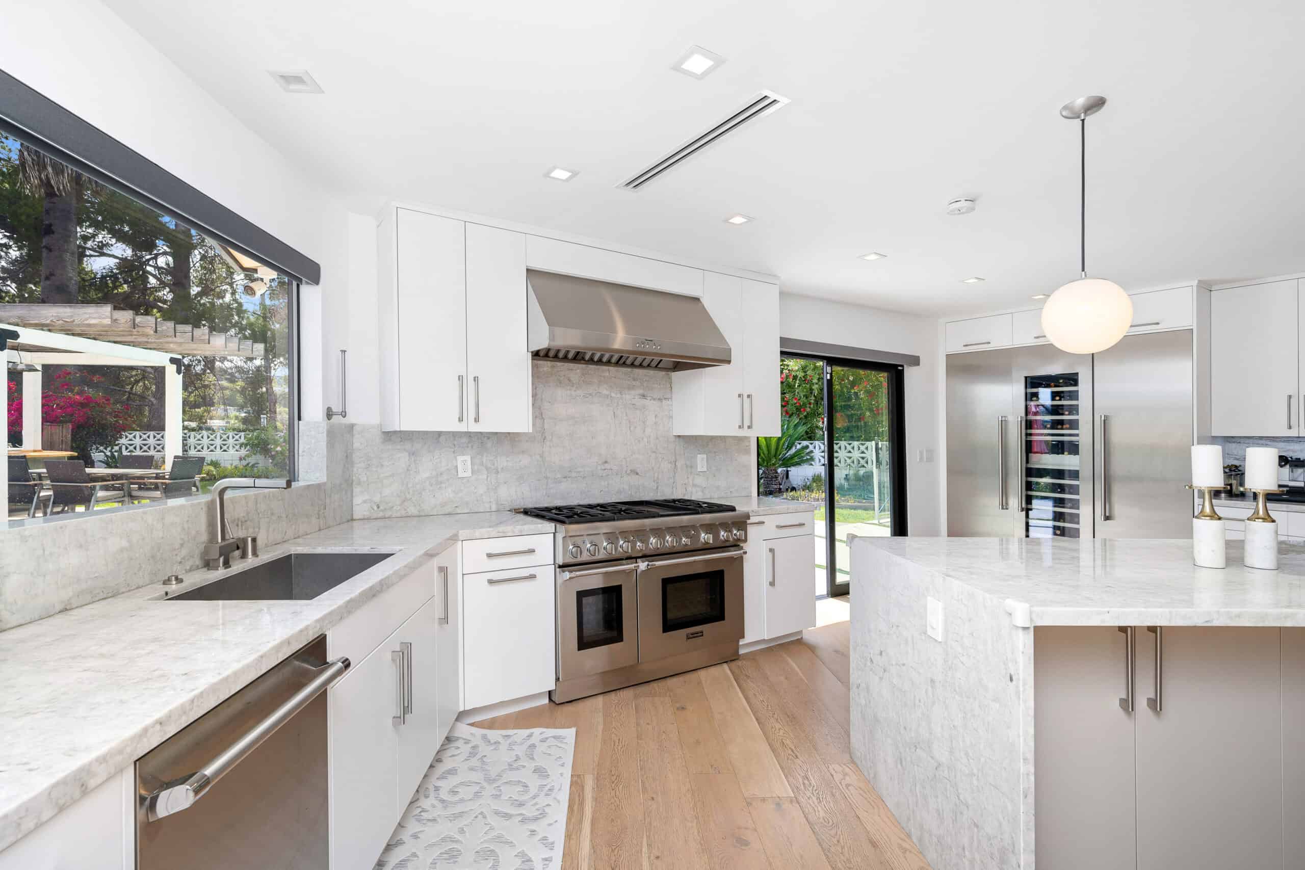 Contemporary kitchen with white cabinets, stainless steel appliances, and marble countertops.