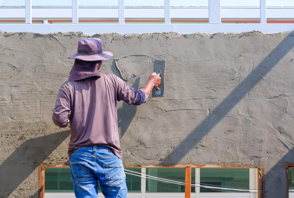 Worker applying finishing to concrete wall for construction project.