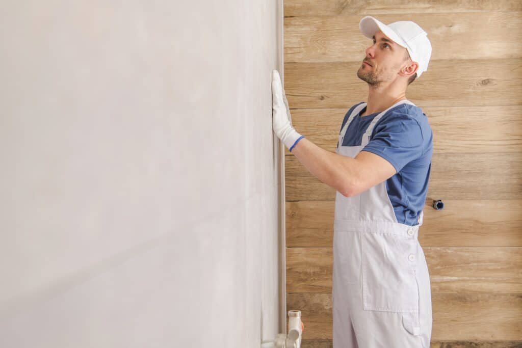 Professional painter applying paint to interior wall for home renovation.
